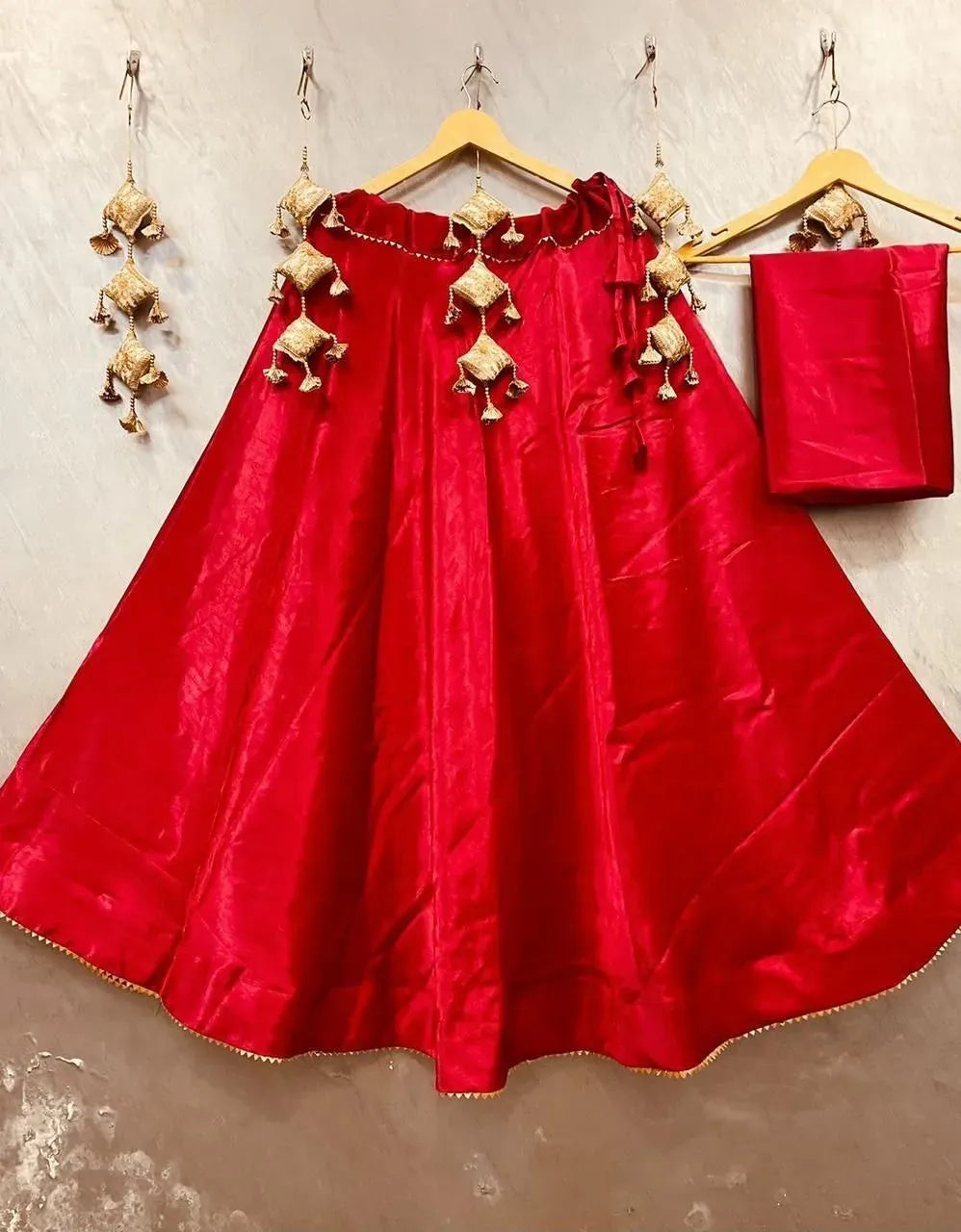 Bright red semi gaji silk stitched lehenga with gold hanging tassels and matching blouse piece