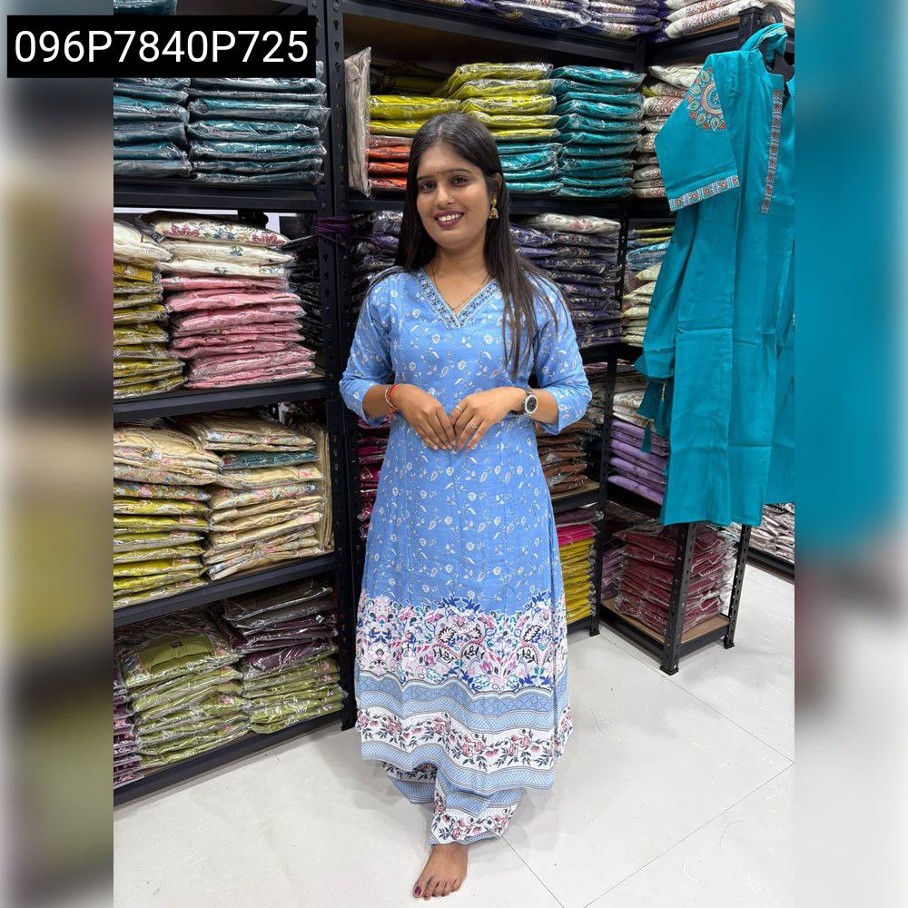 Woman posing front-facing in a beautiful blue floral hand work V-neck kurta palazzo set with bare feet.