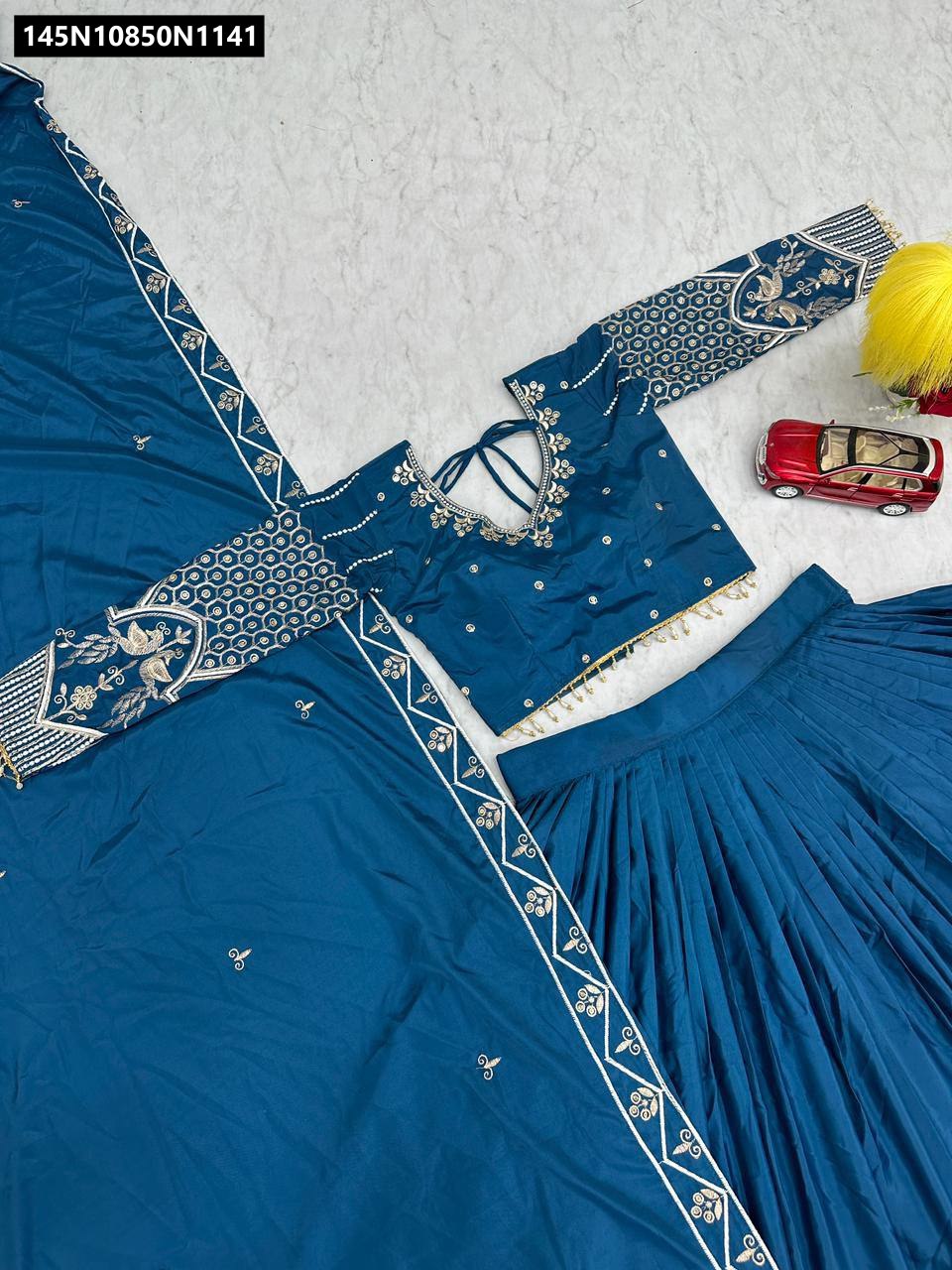 Close-up of intricate gold and silver thread embroidery on teal blue silk fabric
