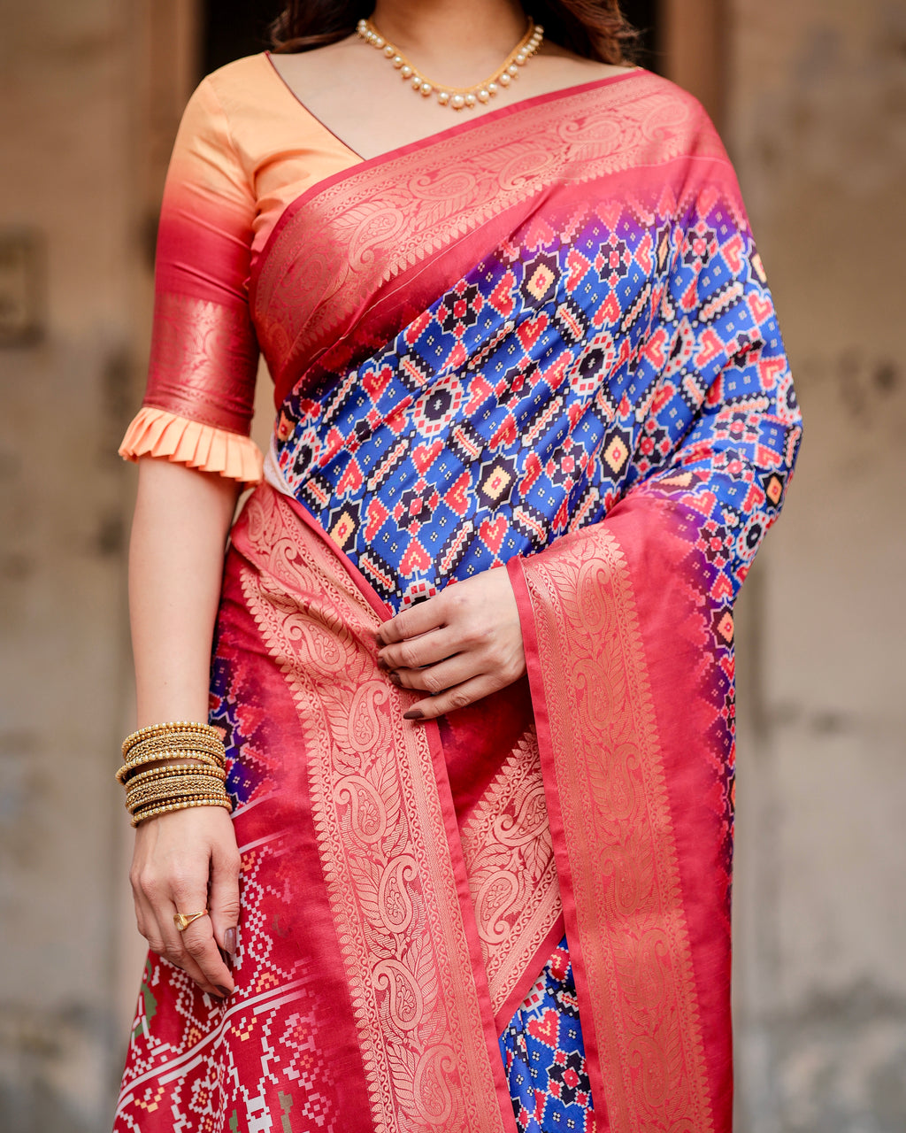 Close-up shot of a woman's midsection showcasing the intricate Ikat digital print and rich red Zari border of a silk saree.