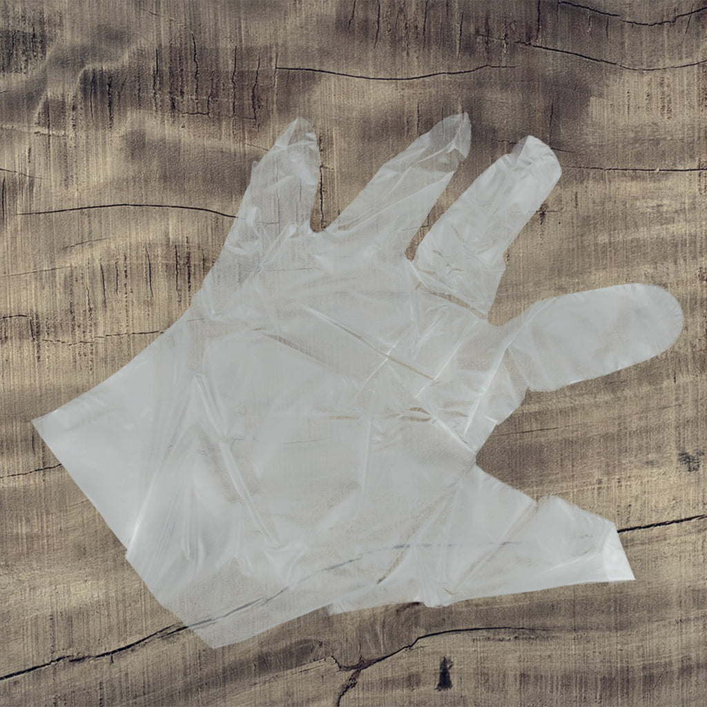 Close-up of a hand wearing a transparent plastic glove showing textured grip surface.