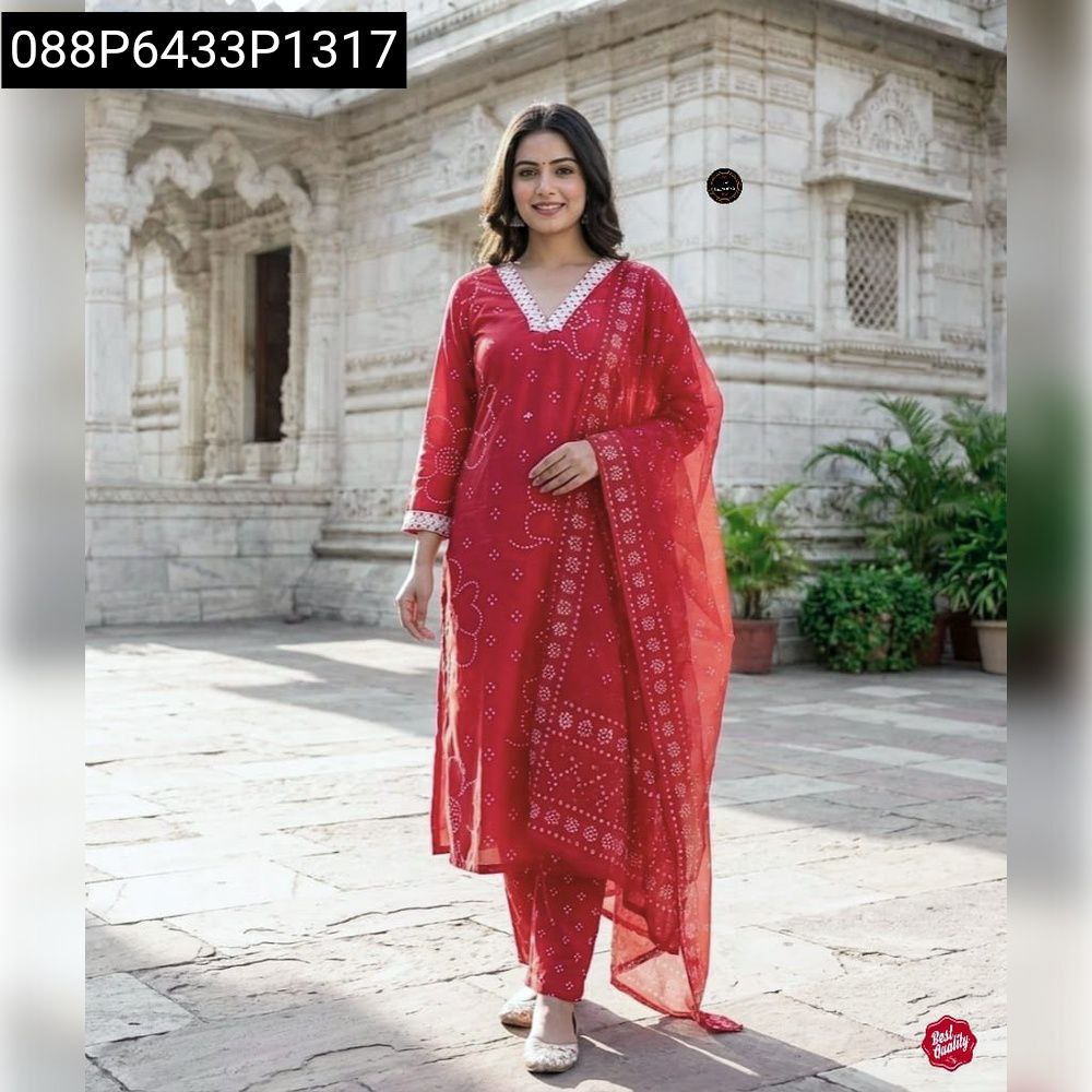Smiling woman in a red embroidered rayon kurti set with a matching dupatta, posing elegantly in front of traditional architecture.