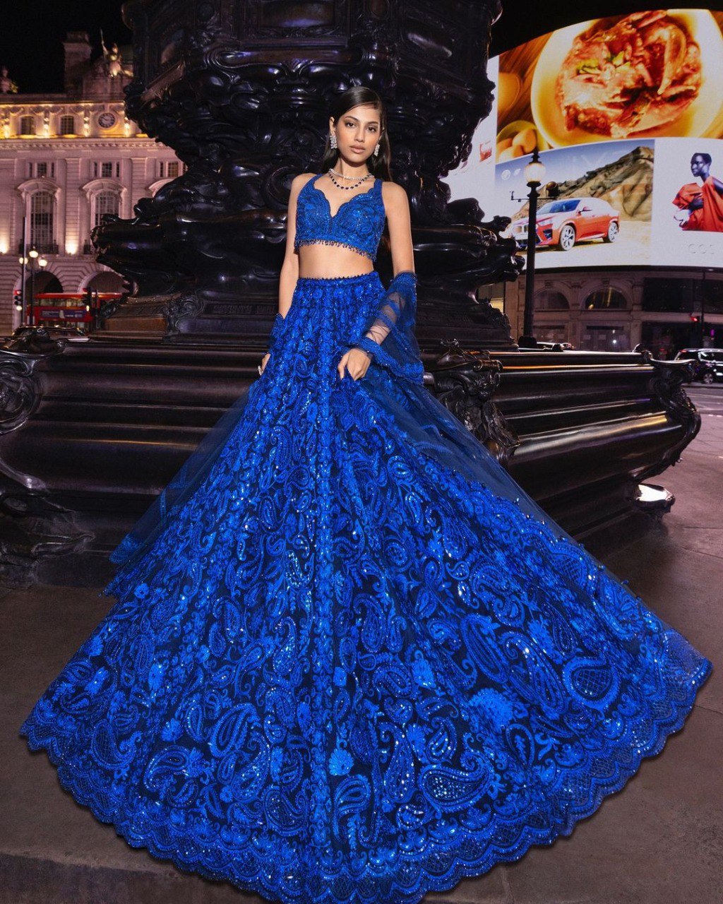 Model in a stunning Royal Blue Sequined Faux Georgette Lehenga, full view, in an urban setting.