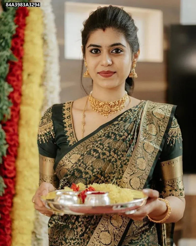 Front view of a woman wearing a Deep Green Lichi Silk Saree, showcasing the rich pallu and jacquard weave, holding a ceremonial plate.