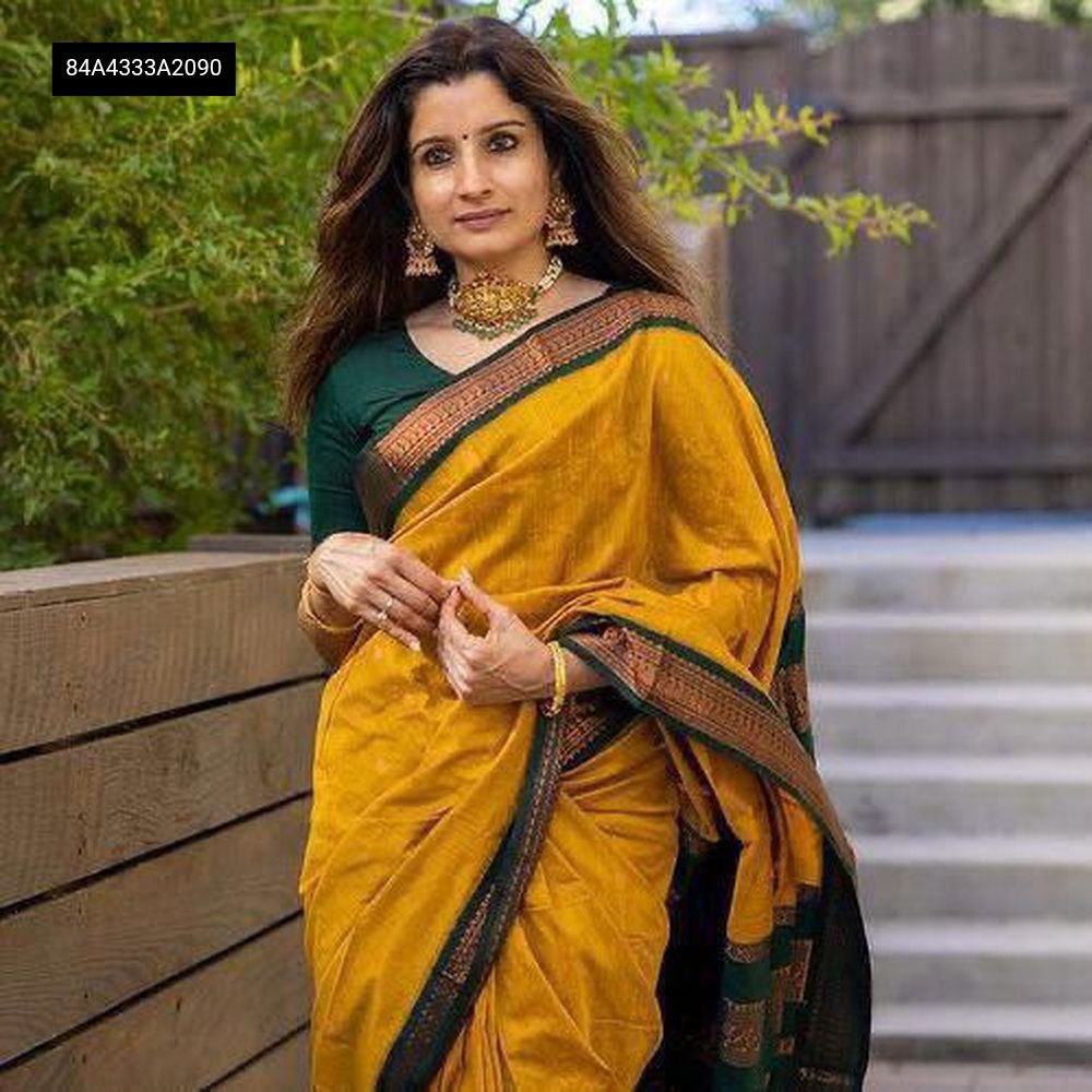 Model in a vibrant yellow Lichi silk saree with green border and pallu, standing outdoors.