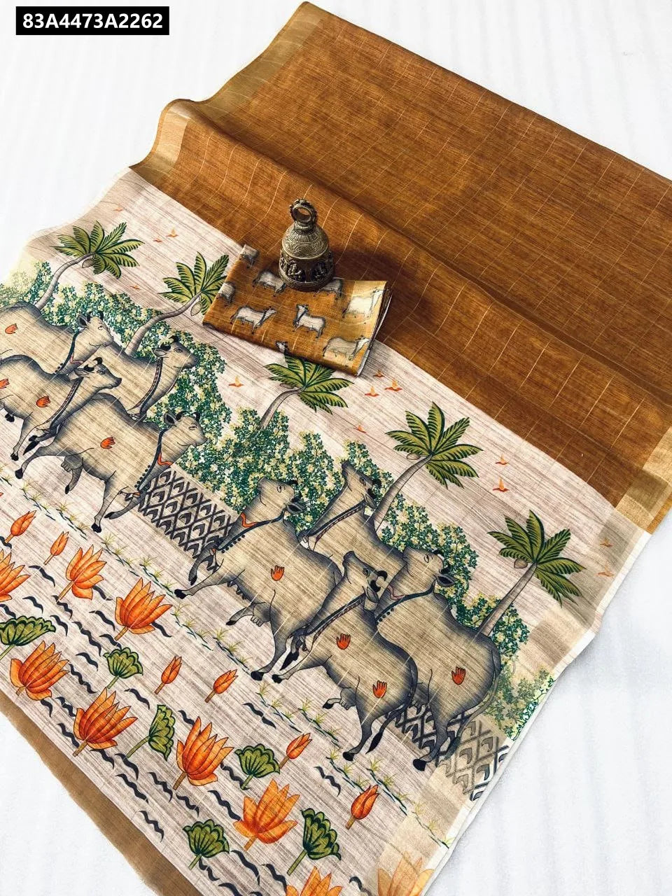 TRENDBUY Linen Digital Print Saree in Rust Brown with cow and lotus motifs, flat lay.