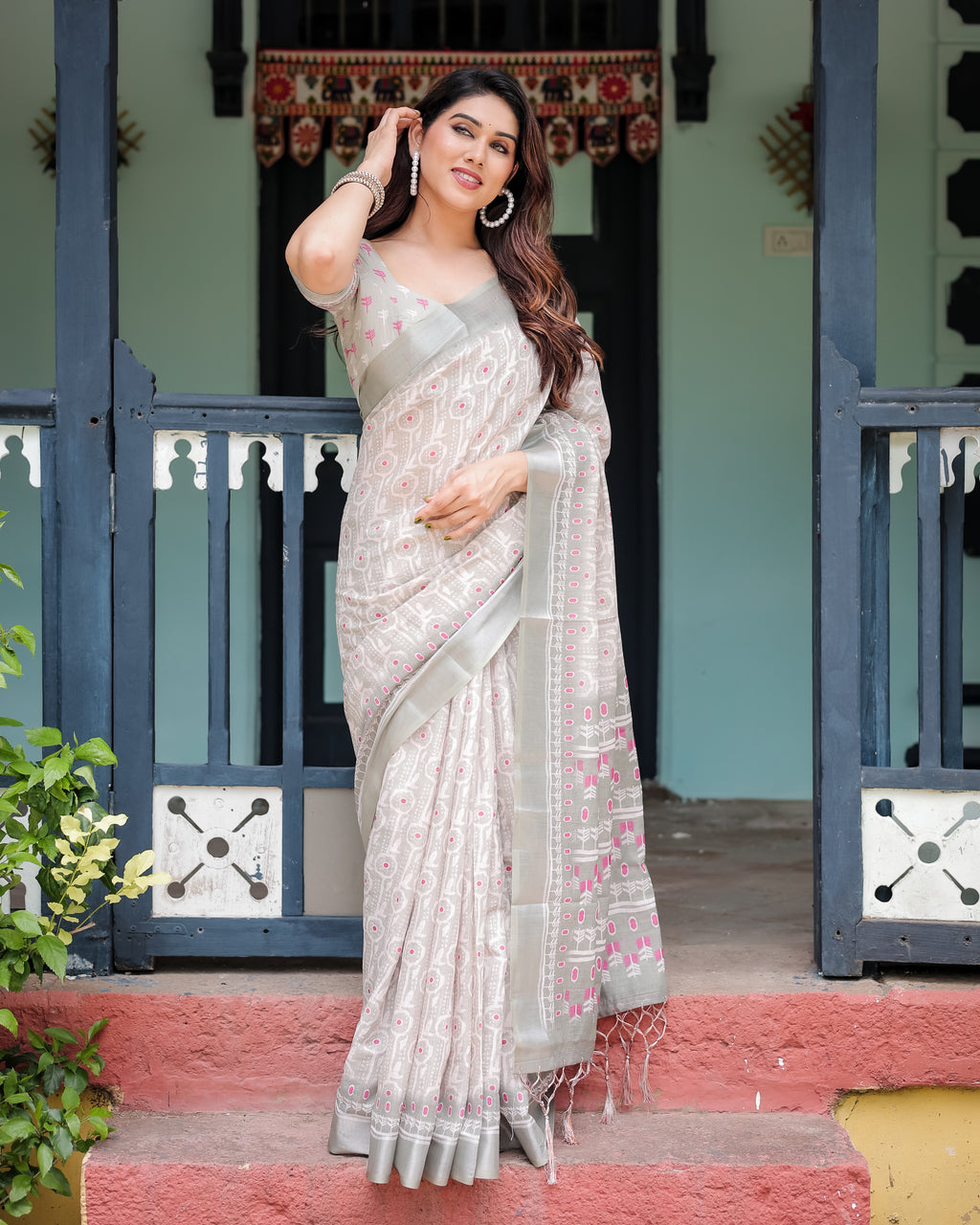 Woman posing in elegant soft grey linen ikat saree with pink accents