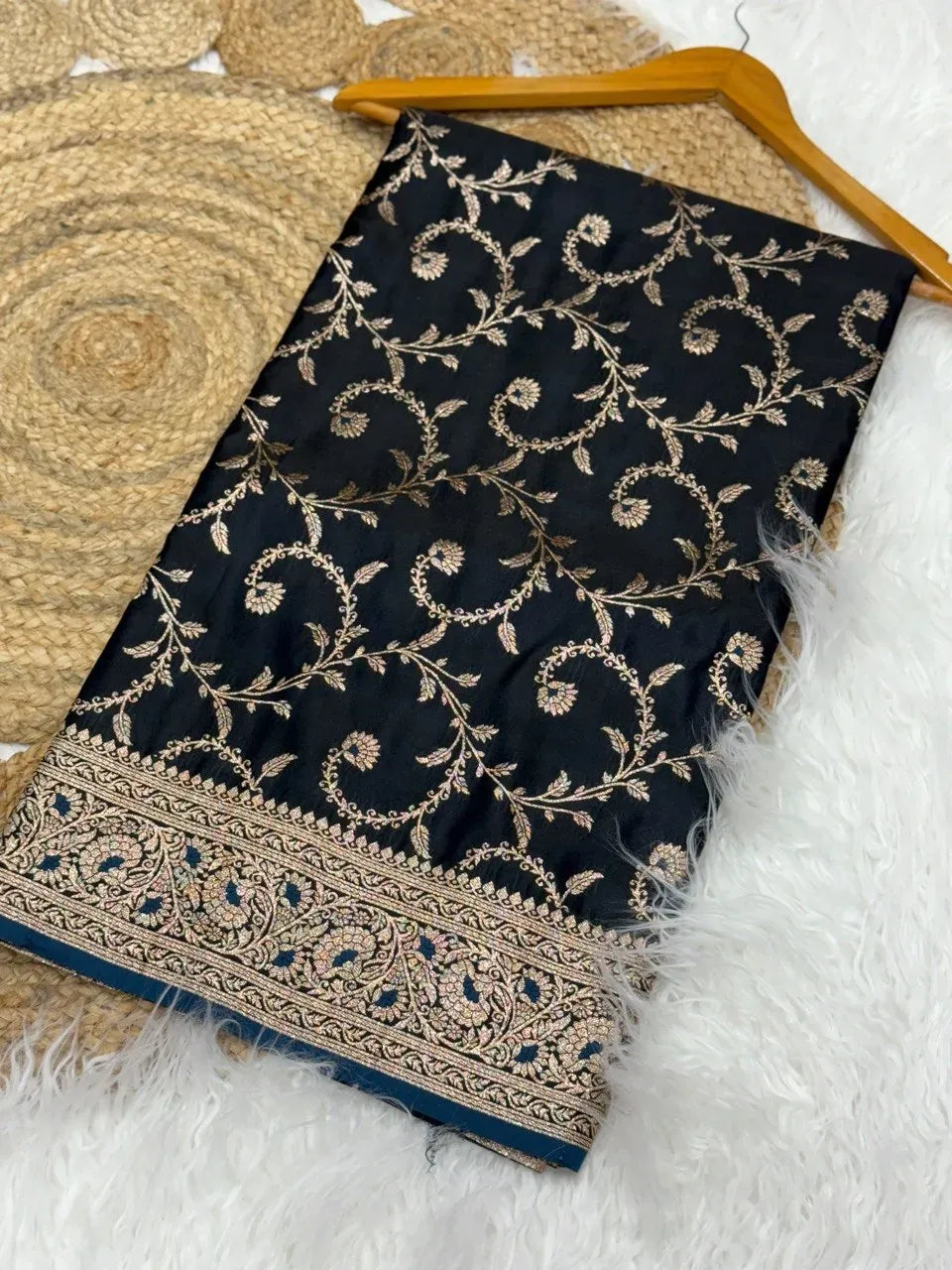 Dual tone satin silk saree folded on white surface with gold zari border