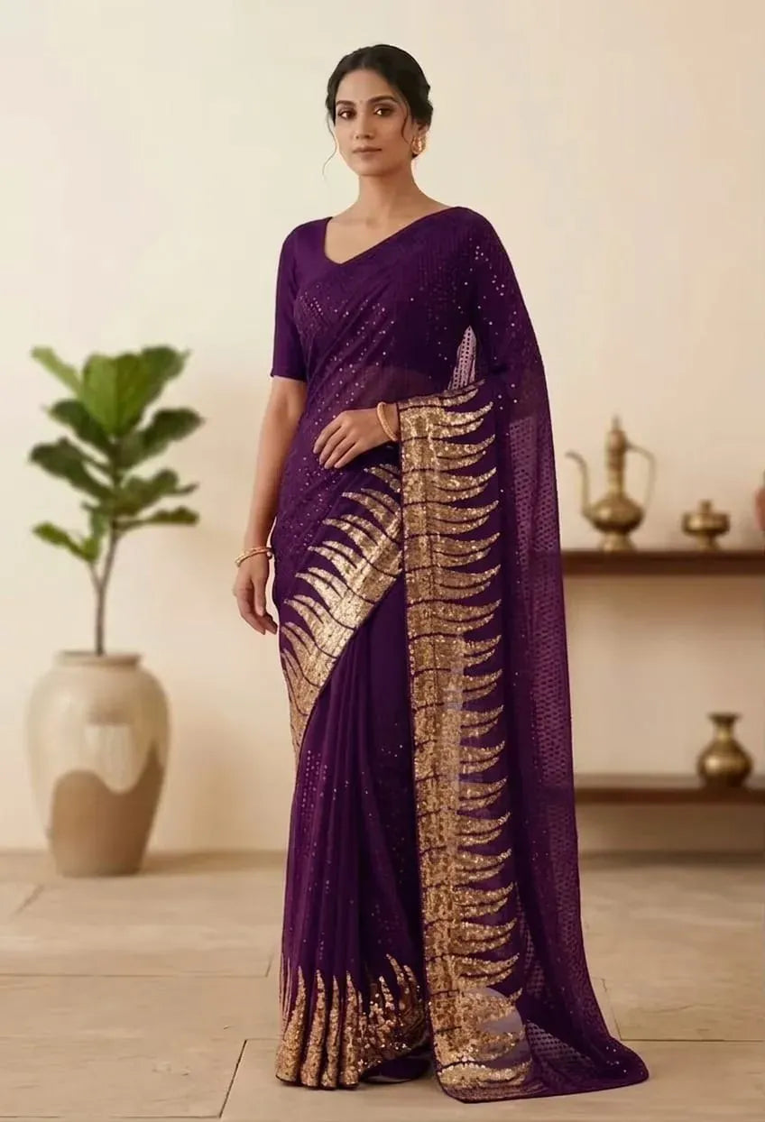 Woman posing in a dark purple georgette saree featuring a thick gold sequined border with leaf patterns