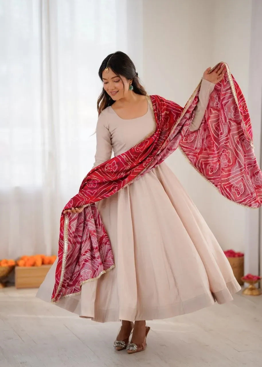 Model wearing beige long roman cotton anarkali gown holding red patterned dupatta