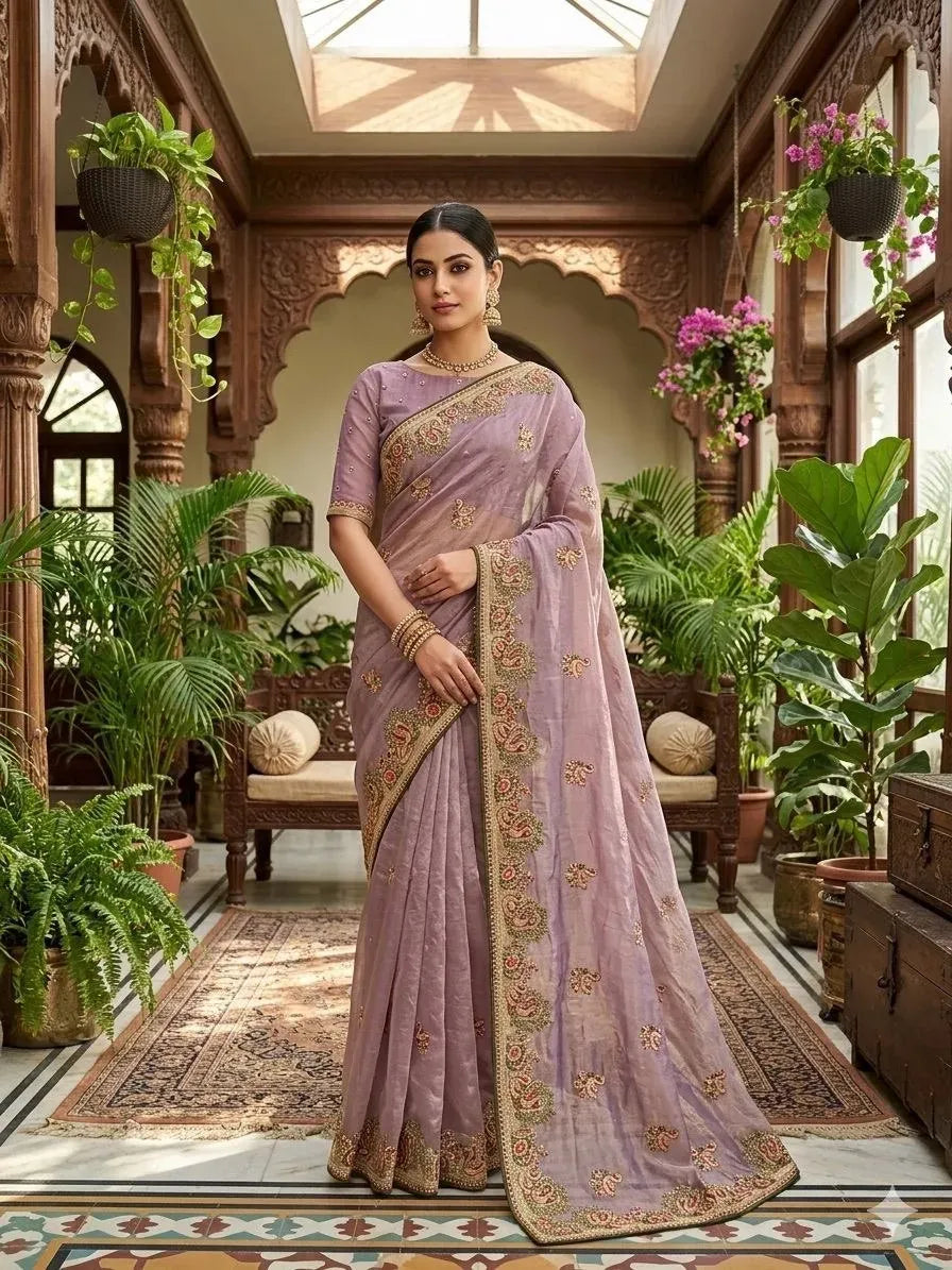 Model sitting gracefully wearing lavender designer satin silk saree in traditional interior