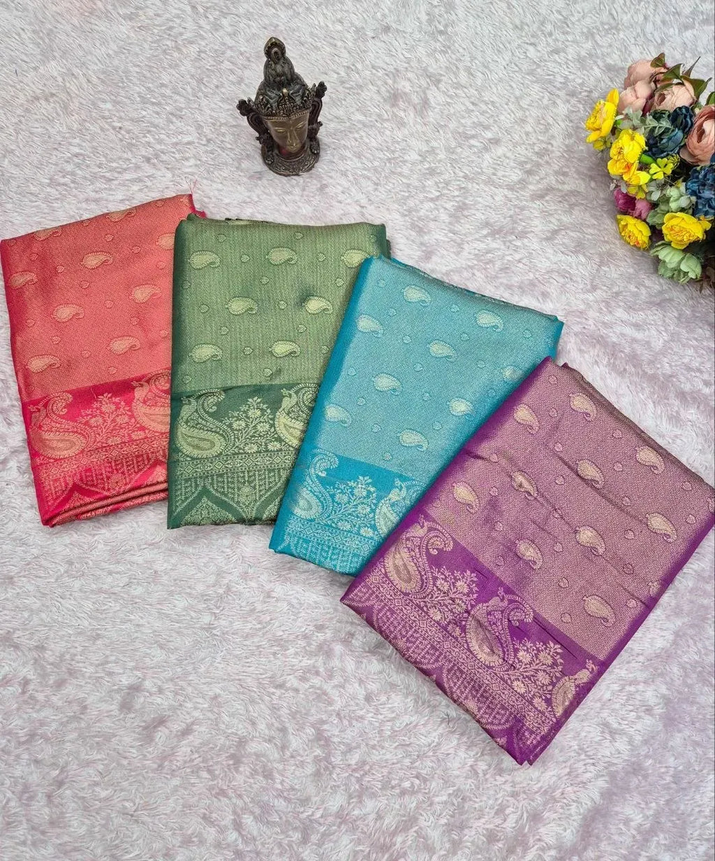 Four folded soft tissue satin silk sarees in red, green, blue, and purple