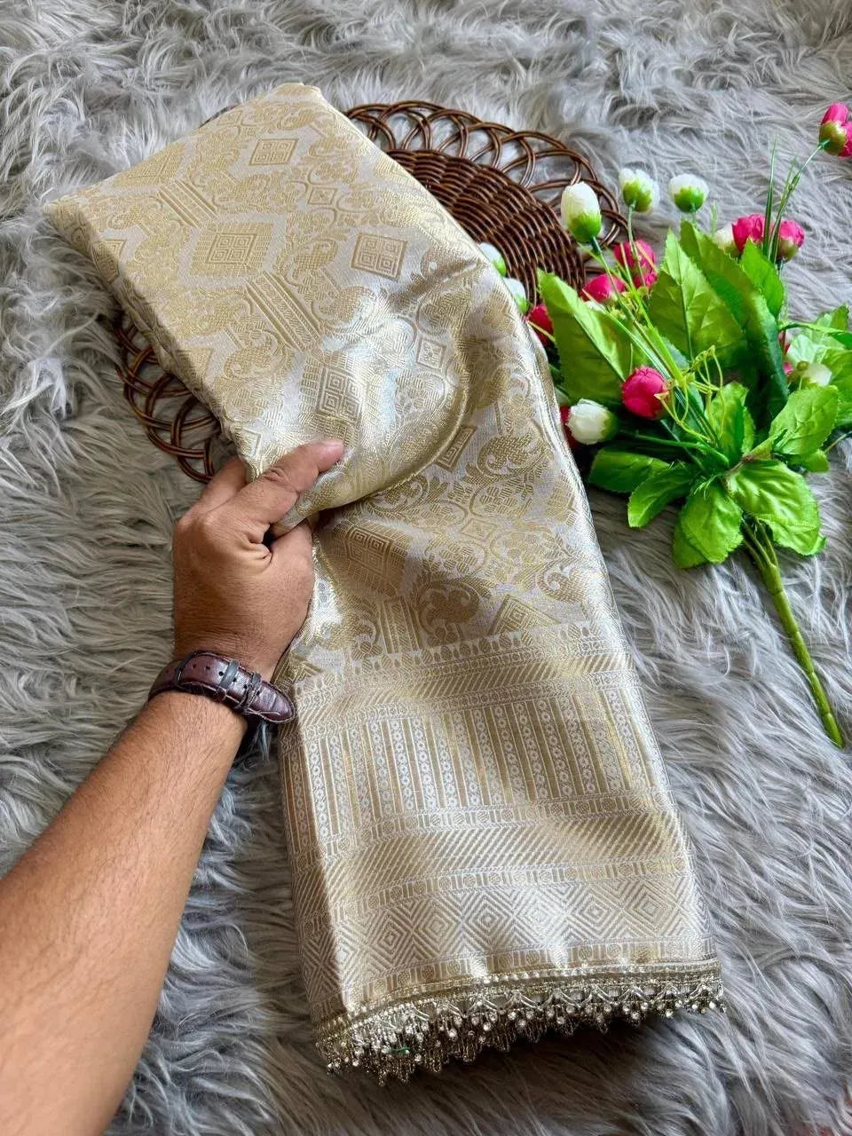 Hand holding folded antique zari Banarasi silk saree with floral decor