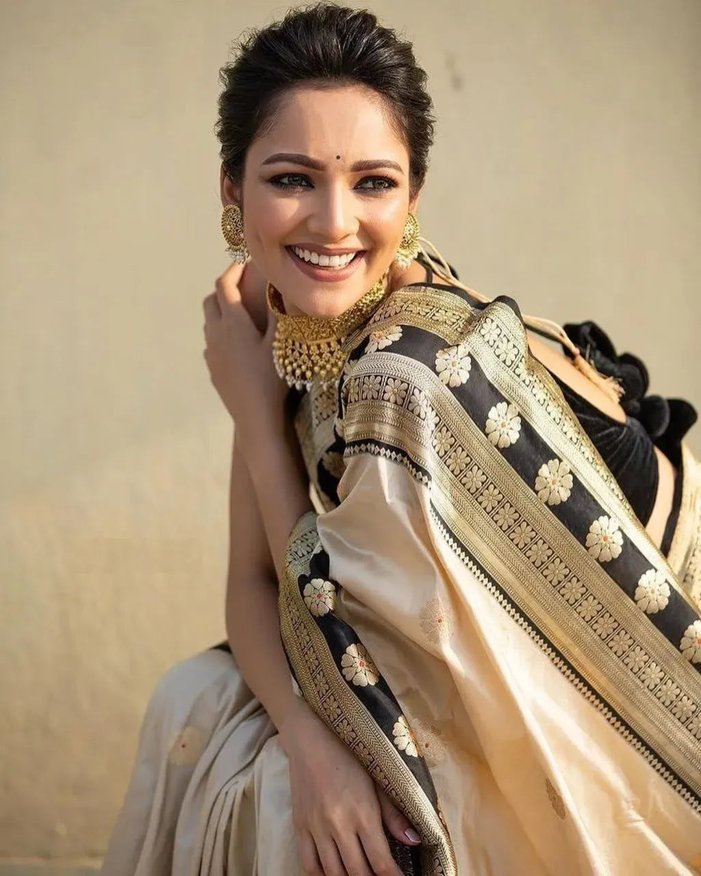 Model smiling gracefully wearing cream and black jacquard soft silk saree