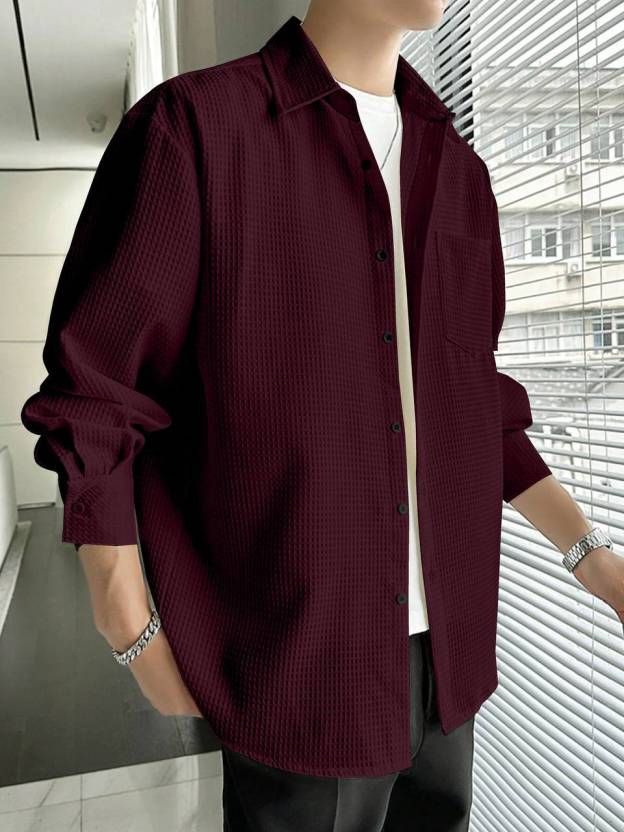 Person wearing a burgundy textured shirt in an indoor setting