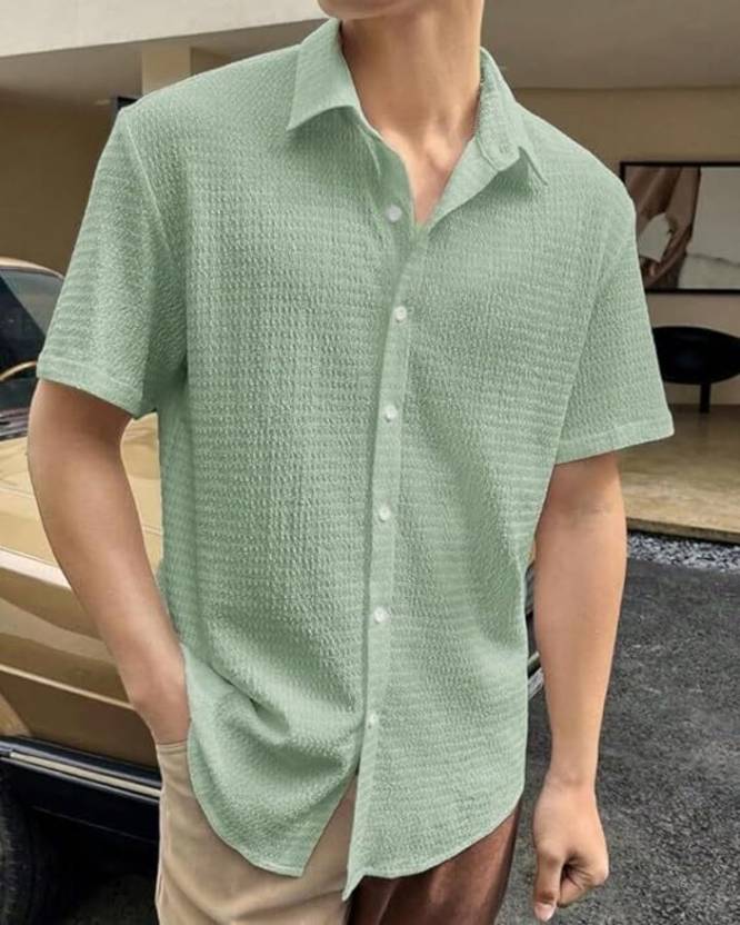 Person wearing a green textured short-sleeve shirt outdoors.