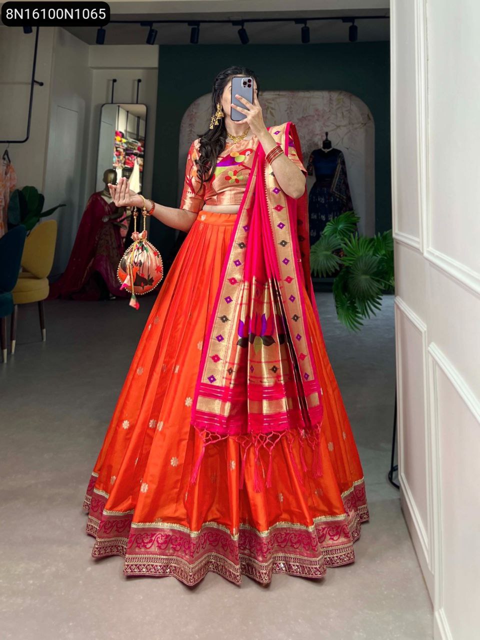 Elegant model posing in an orange Paithani Jacquard Silk Lehenga Choli with intricate zari weaving, holding a matching batwa.