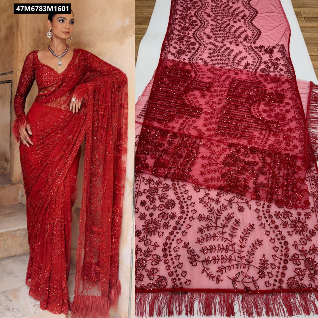 Woman wearing a red heavy butterfly net saree with extensive sequin embroidery and feathered sleeves, posing on stairs.