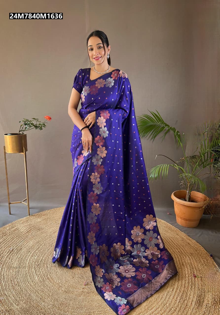 Model smiling, elegantly draped in a vibrant Royal Blue soft silk saree with intricate copper and gold floral weaving, standing on a woven rug.