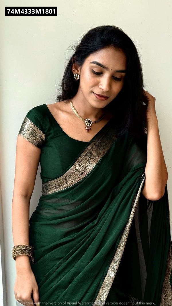 A woman gracefully posing, draped in an Emerald Green Rangoli Silk Saree with a golden Jacquard border, paired with a matching blouse and delicate jewelry.