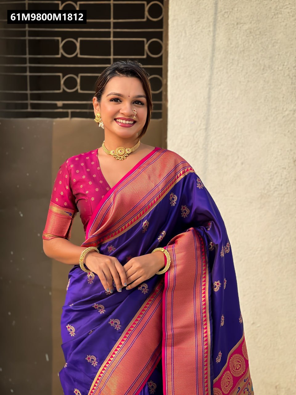 Model smiling, posing in a Royal Purple Soft Silk Saree with intricate Nath Meenakari weaves and a rich pink Paithani border and pallu, paired with a vibrant pink brocade blouse.