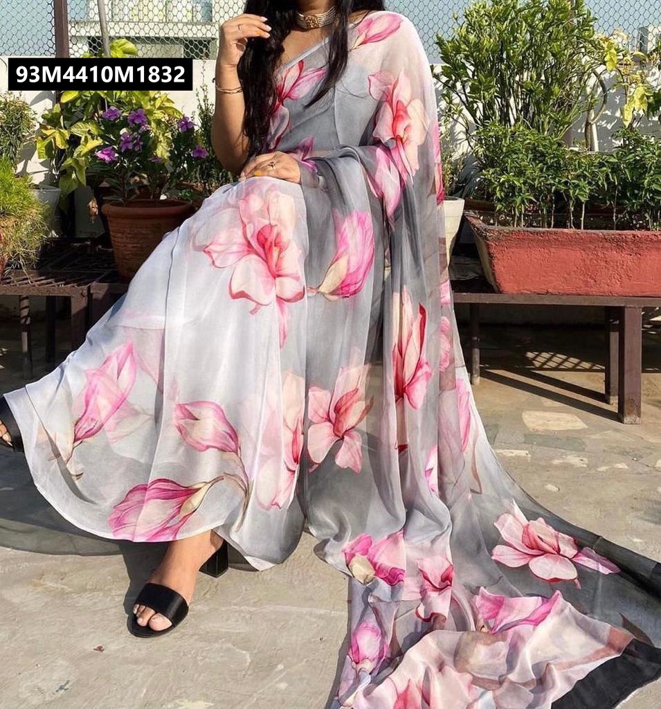 Full view of a model sitting, elegantly draped in the TRENDBUY slate grey georgette printed saree with pink floral patterns, showcasing the graceful drape and flow.