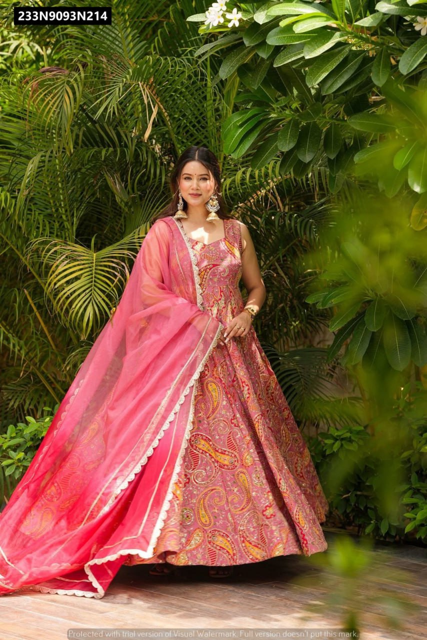 Full shot of a model wearing a pink digital printed Anarkali gown with a pink organza dupatta, posing outdoors.