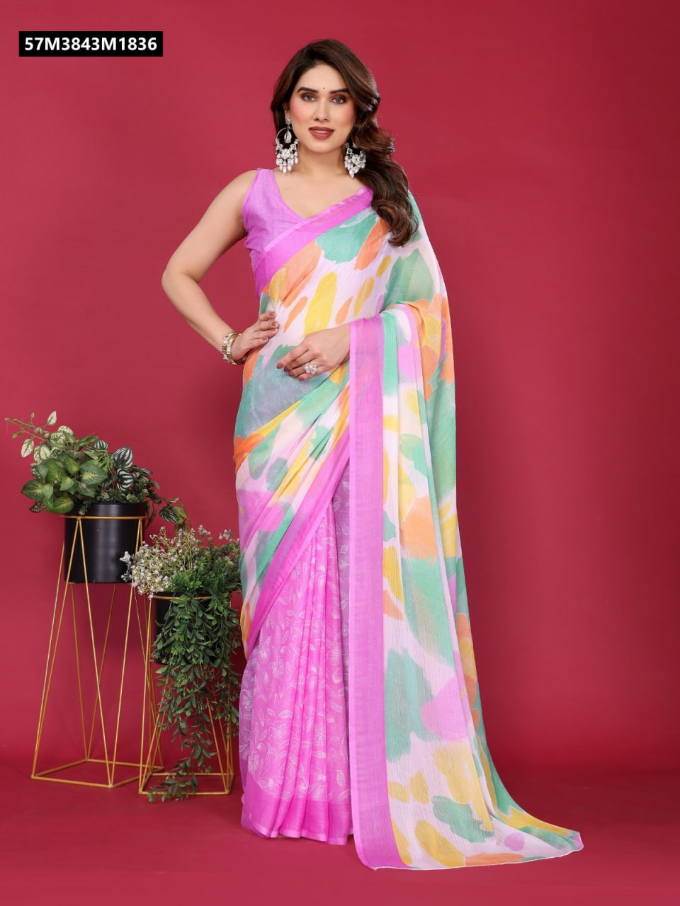 Model posing in a TRENDBUY soft chiffon saree with a pink body and a multi-color abstract printed pallu, against a red background.