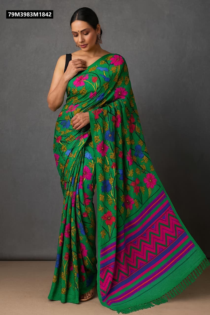 A woman elegantly drapes a vibrant green blooming mul georgette saree with abstract floral prints in pink, blue, and golden hues, featuring a geometric border.