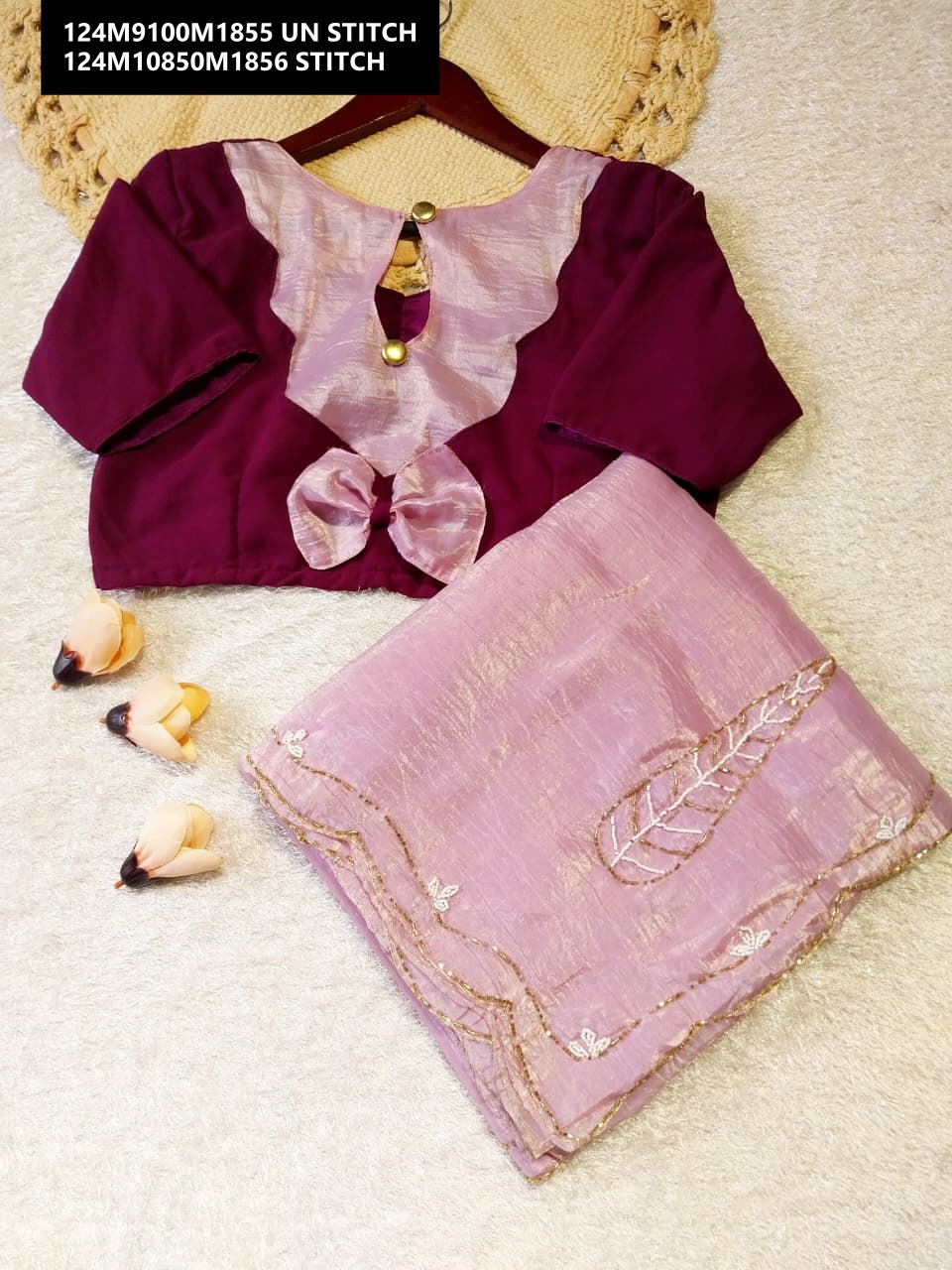 Close-up of a deep maroon blouse featuring a light pink ruffled neckline and a delicate bow detail, paired with a folded light pink Candy Gold Crush saree with fine handwork.