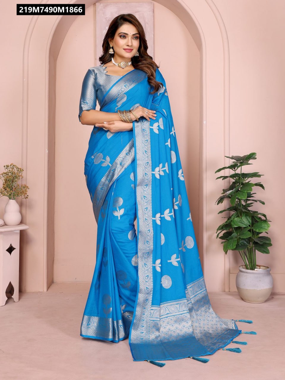 A model in a bright blue soft georgette silk Banarasi saree with silver zari weaving floral butta and border, posing elegantly.