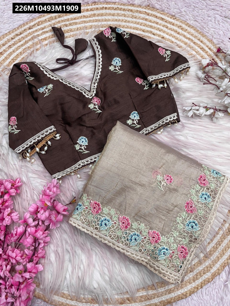 TRENDBUY Gold Karsh Saree set featuring a brown Mono Banglori embroidered blouse and a matching taupe beige saree, laid out on a white textured mat with pink flowers.