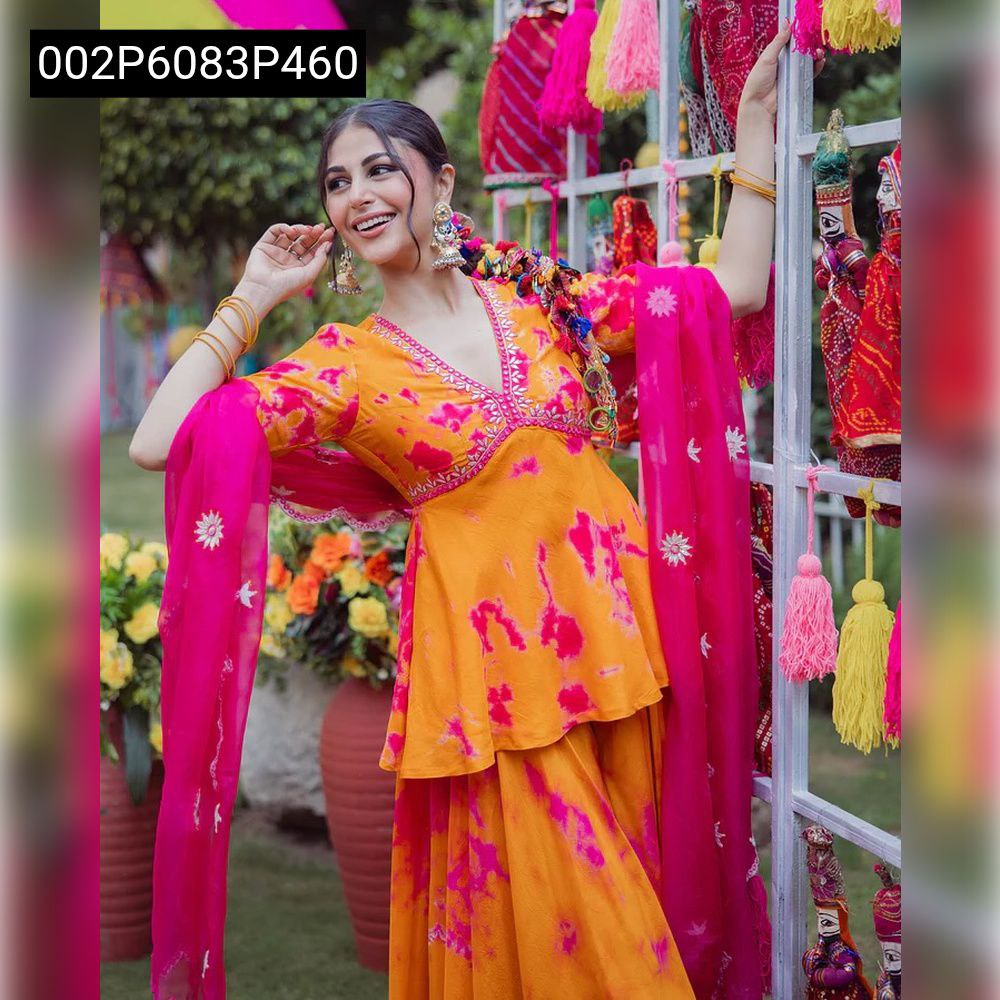 Model posing in a vibrant orange and hot magenta French Crepe three-piece Indian ethnic wear set with flared top and sheer dupatta, smiling against a festive backdrop.
