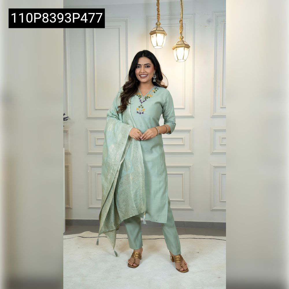 Full-body shot of a smiling model wearing a C Green Roman Silk kurta set with an embroidered V-neck and a matching jacquard dupatta, hands clasped, standing in a white room.
