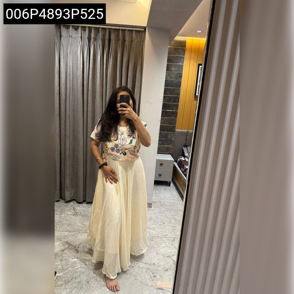 Model in a light beige TRENDBUY Chinnon silk Anarkali gown, full body shot in a mirror, showing the elegant embroidery and flowing skirt.