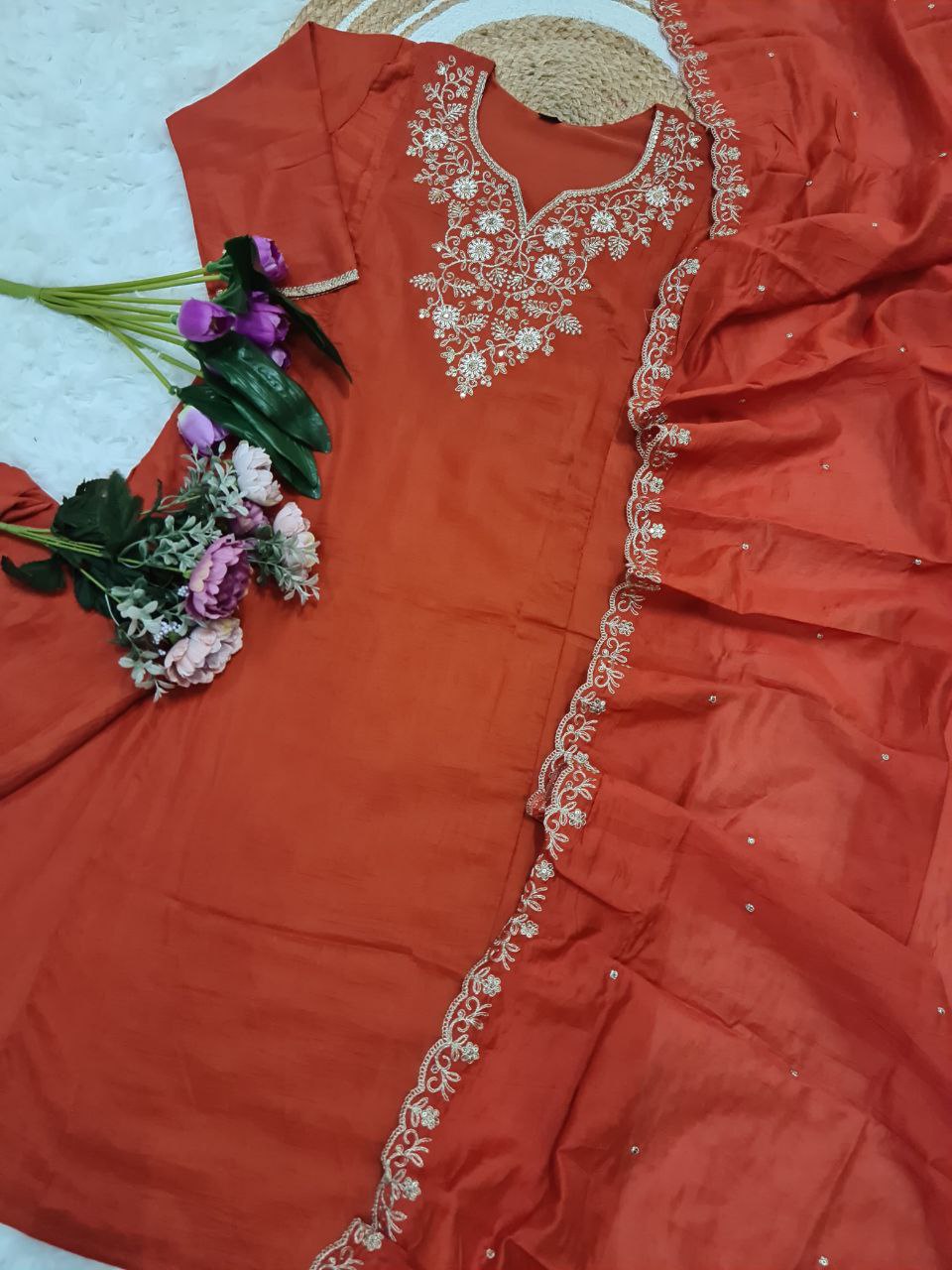 Overhead shot of the orange kurta set components, showcasing the full design of the embroidered kurta, pant, and dupatta with floral accents.