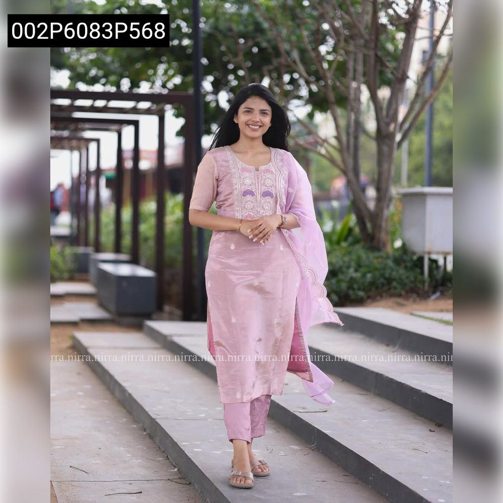 Full body shot of a smiling model walking outdoors, showcasing a lavender Chinon embroidered kurti, matching pants, and a flowing net dupatta.