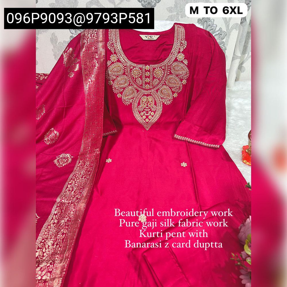 Full view of a stunning Fuchsia Red Gajji Silk Kurta Set with rich golden embroidery, a gracefully draped Banarasi jacquard dupatta, and coordinated pants, presented on a textured background with a pearl necklace.