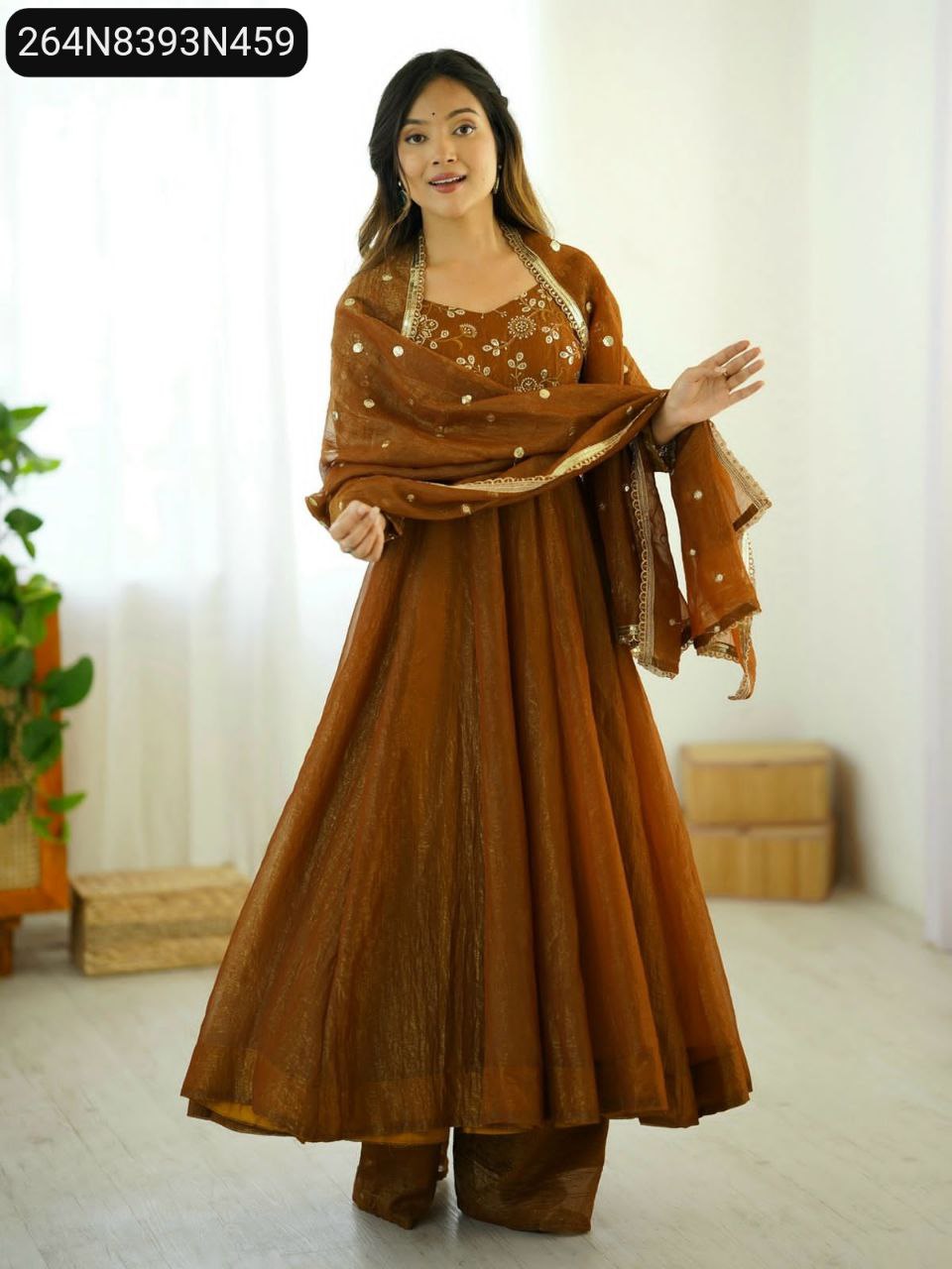 TRENDBUY model posing in a full Rust Gold crunchy silk anarkali gown with golden embroidery and lace-bordered dupatta, full body shot.
