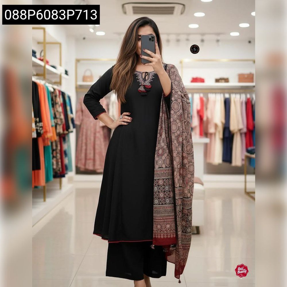 Full body shot of a woman in a black hand-embroidered suit set with Zari weaving dupatta, posing in a boutique.