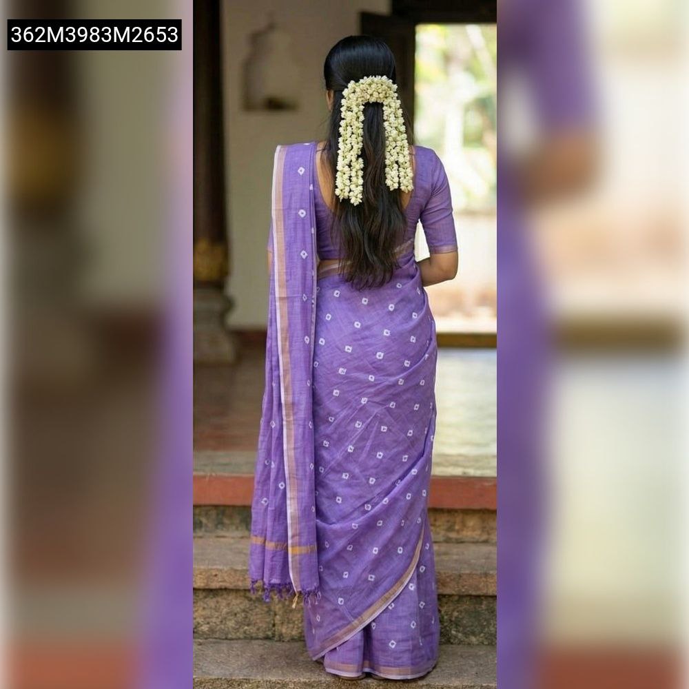 Back view of a woman elegantly draped in a lavender purple TRENDBUY Slub Linen Silk saree, featuring delicate white dotted patterns and a golden border. Her hair is adorned with fresh white jasmine flowers.