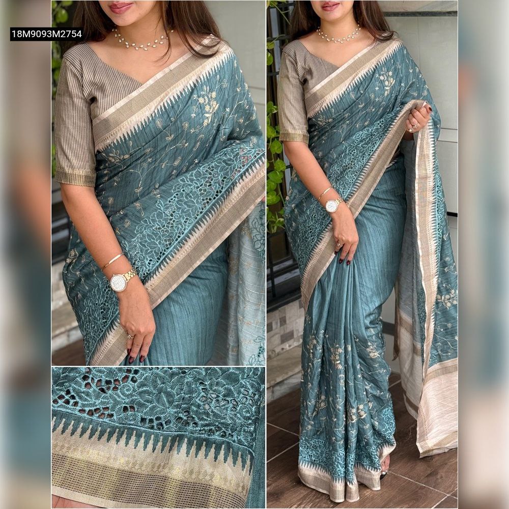 Cropped view of a woman gracefully posing in a TRENDBUY teal tusser cotton saree with intricate golden thread embroidery and a delicate boaring (cutwork lace) border, paired with a striped zari jacquard blouse.
