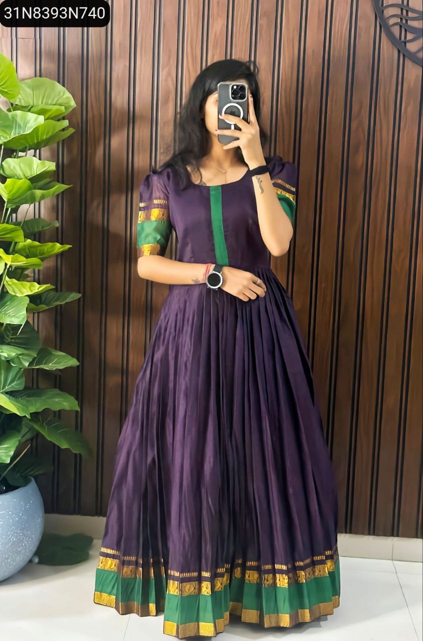 Model wearing a Lavender Cotton Gown with green and gold Zari border, standing in front of a wooden wall.