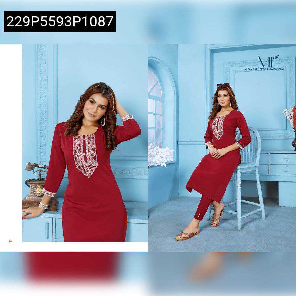 Model posing in a red embroidered Rinkal Cotton kurti and pant set, against a blue background.