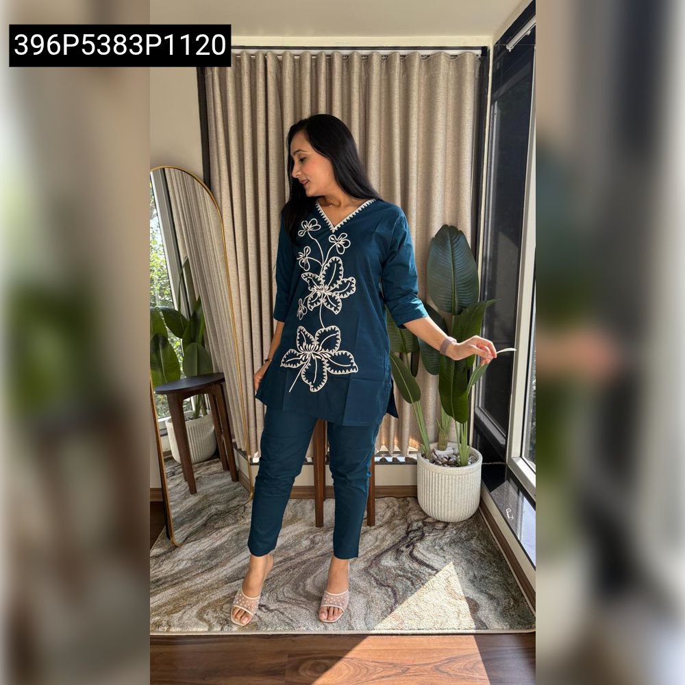 Woman posing gracefully in a dark teal Dhabu cotton V-neck kurta and pant set with white floral embroidery, side view