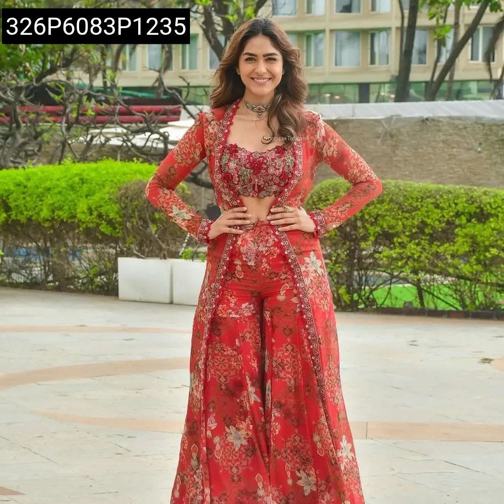 Full body shot of a woman in a red floral digital print georgette jacket, blouse, and plazo set, smiling outdoors.