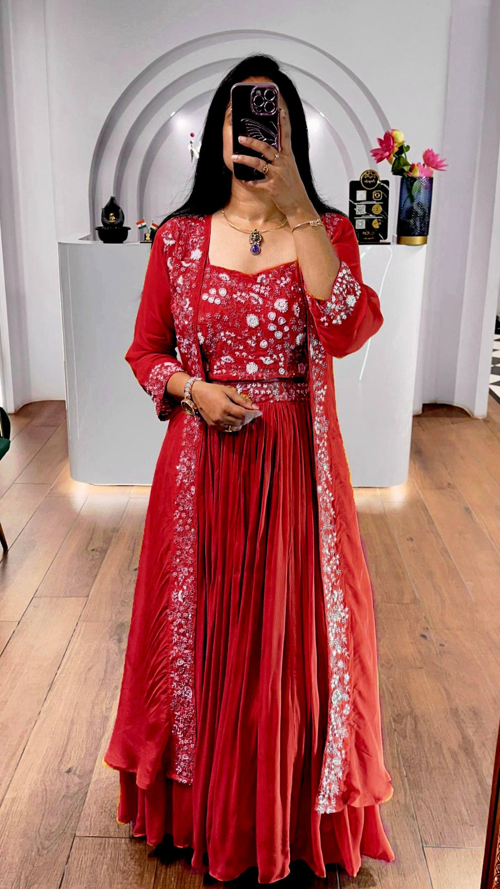 Model in red embroidered Indowestern lehenga choli set with shrug, full body shot.