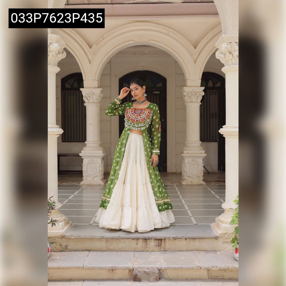 Full-body shot of a model elegantly posing in a green Bandhani print kurti with Kutchi patchwork and a tiered white Kora cotton lehenga in an arched pathway.