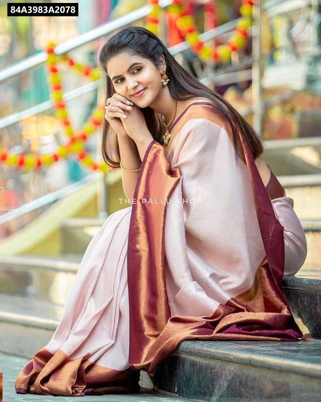 Woman in elegant blush pink and maroon lichi silk jacquard saree by TRENDBUY, seated gracefully.