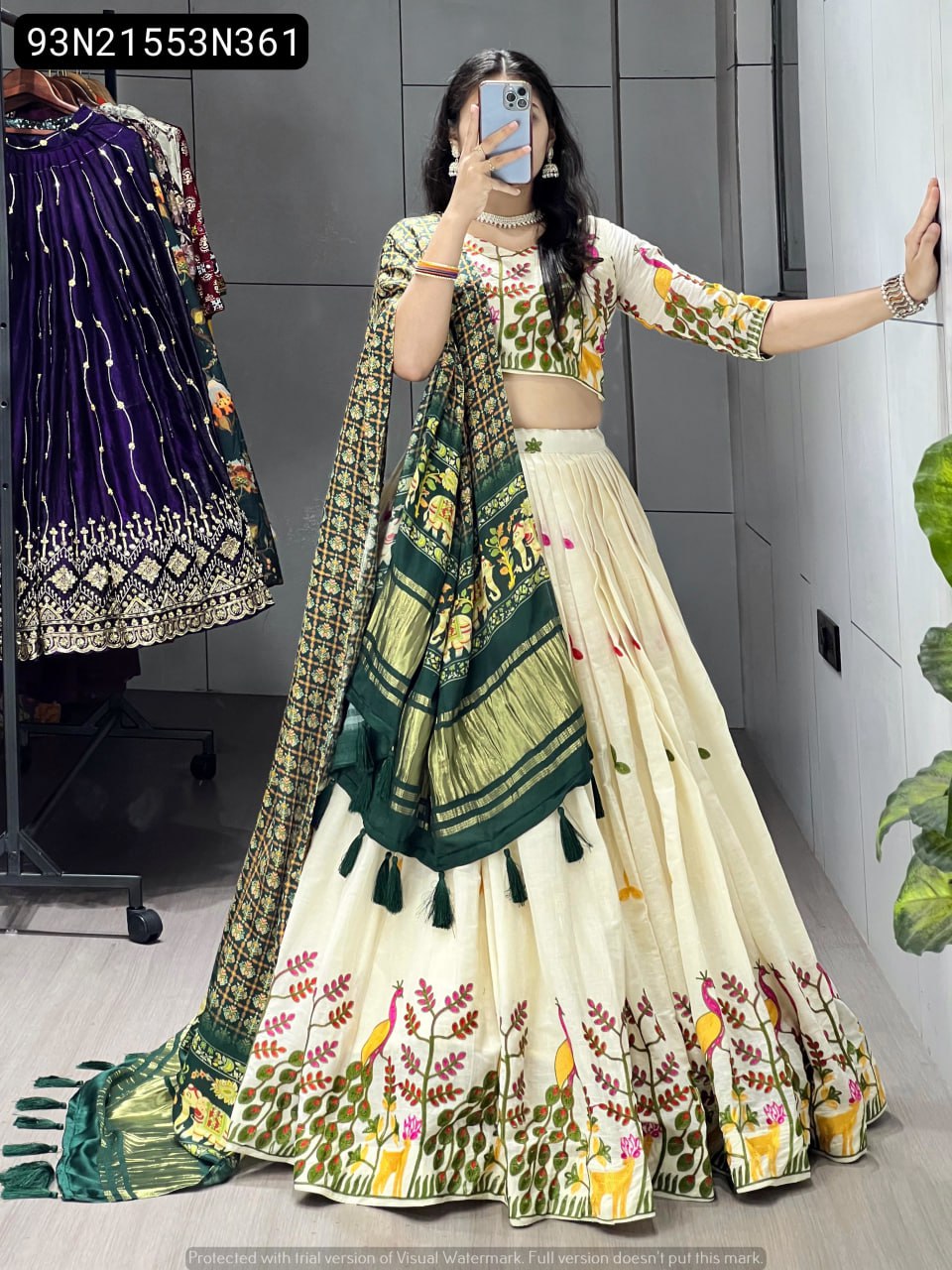 Model in a cream embroidered cotton lehenga and a draped forest green Gaji silk dupatta with tassels, showing the full length and flair of the outfit.